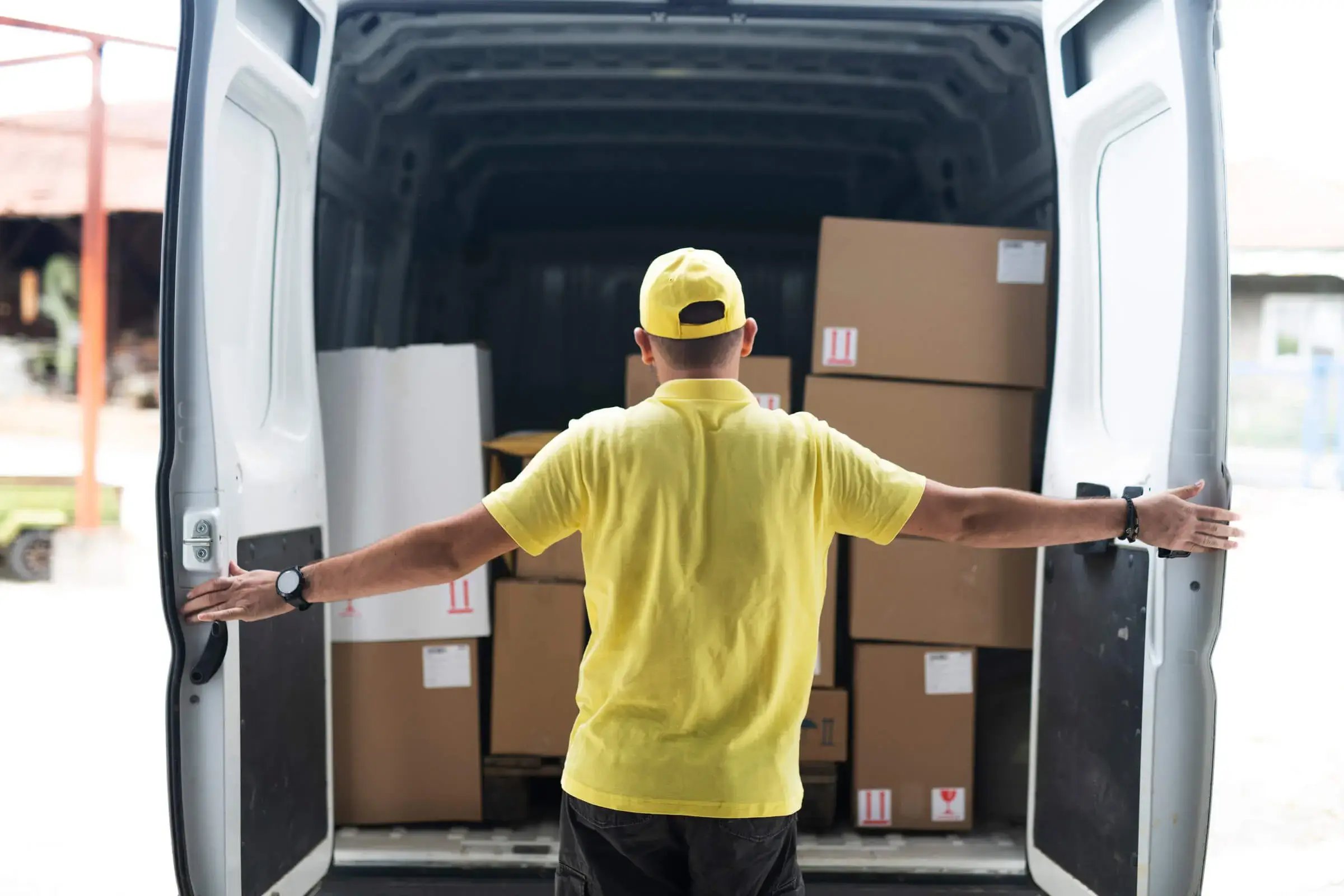 man with yellow cap and top loading up his self drive van hire