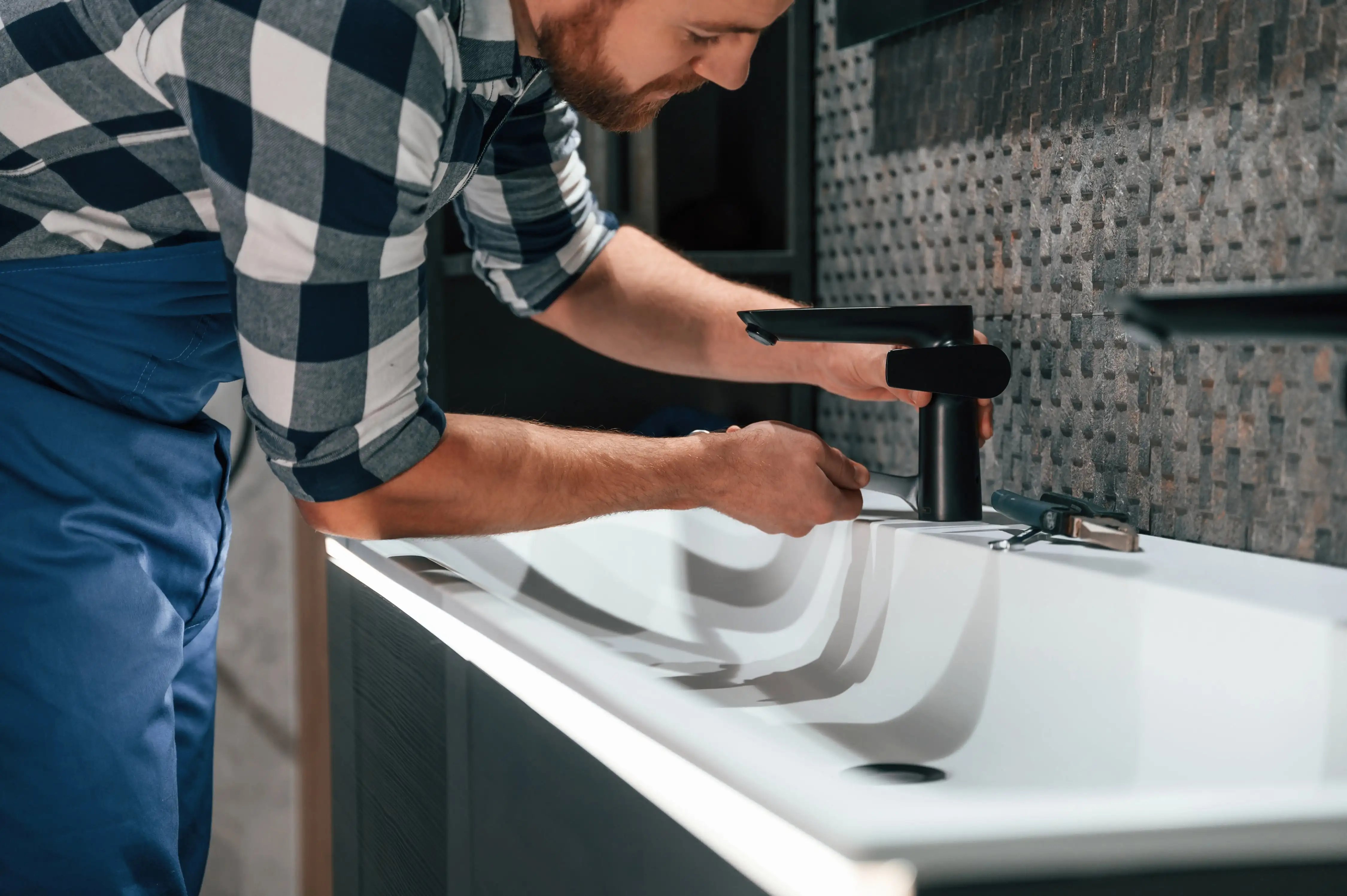 Man fitting sink tap undergoing full DIY bathroom renovation with a hirefleet self drive van hire.