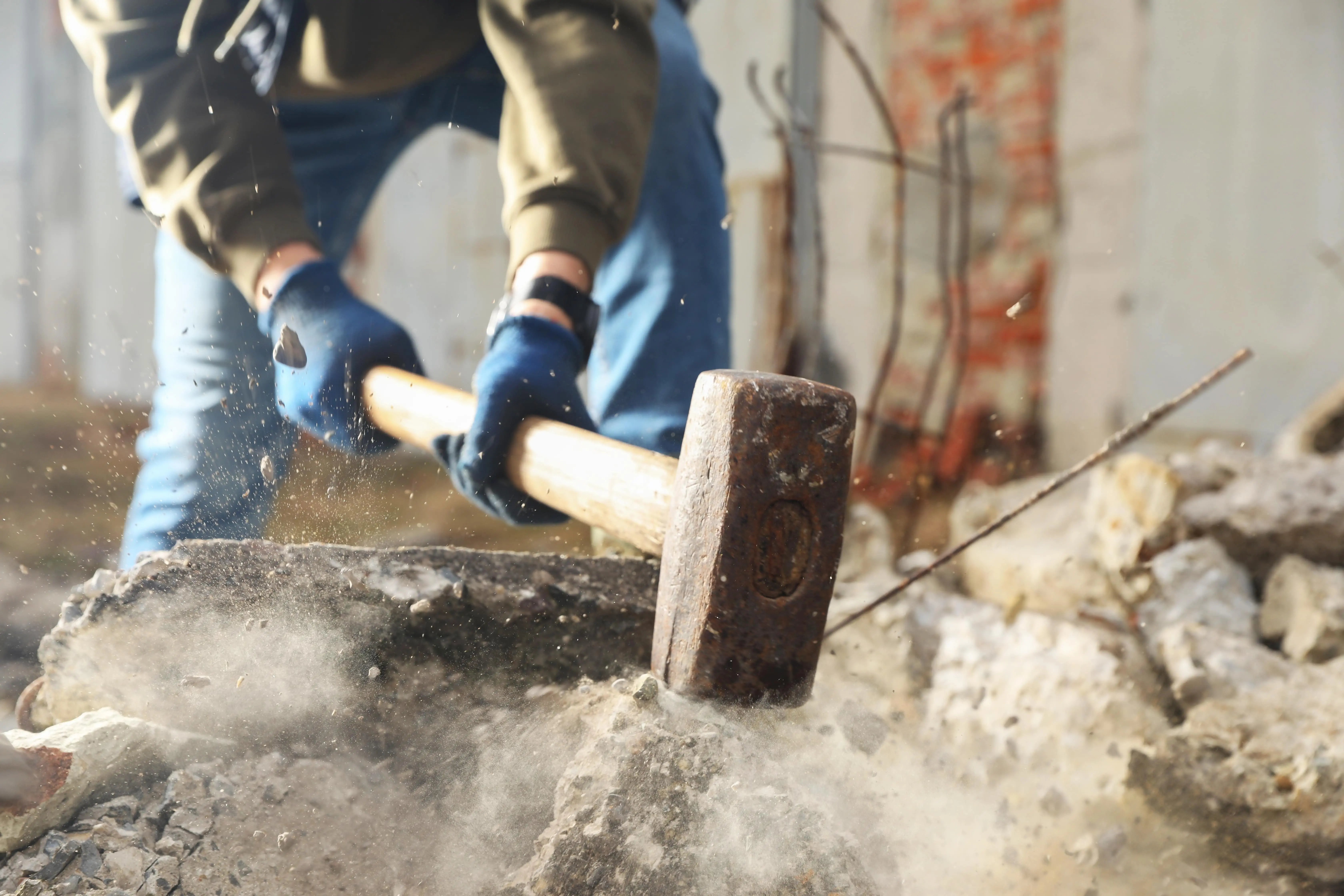 construction worker creating debris with sledgehammer in need of commercial waste removal