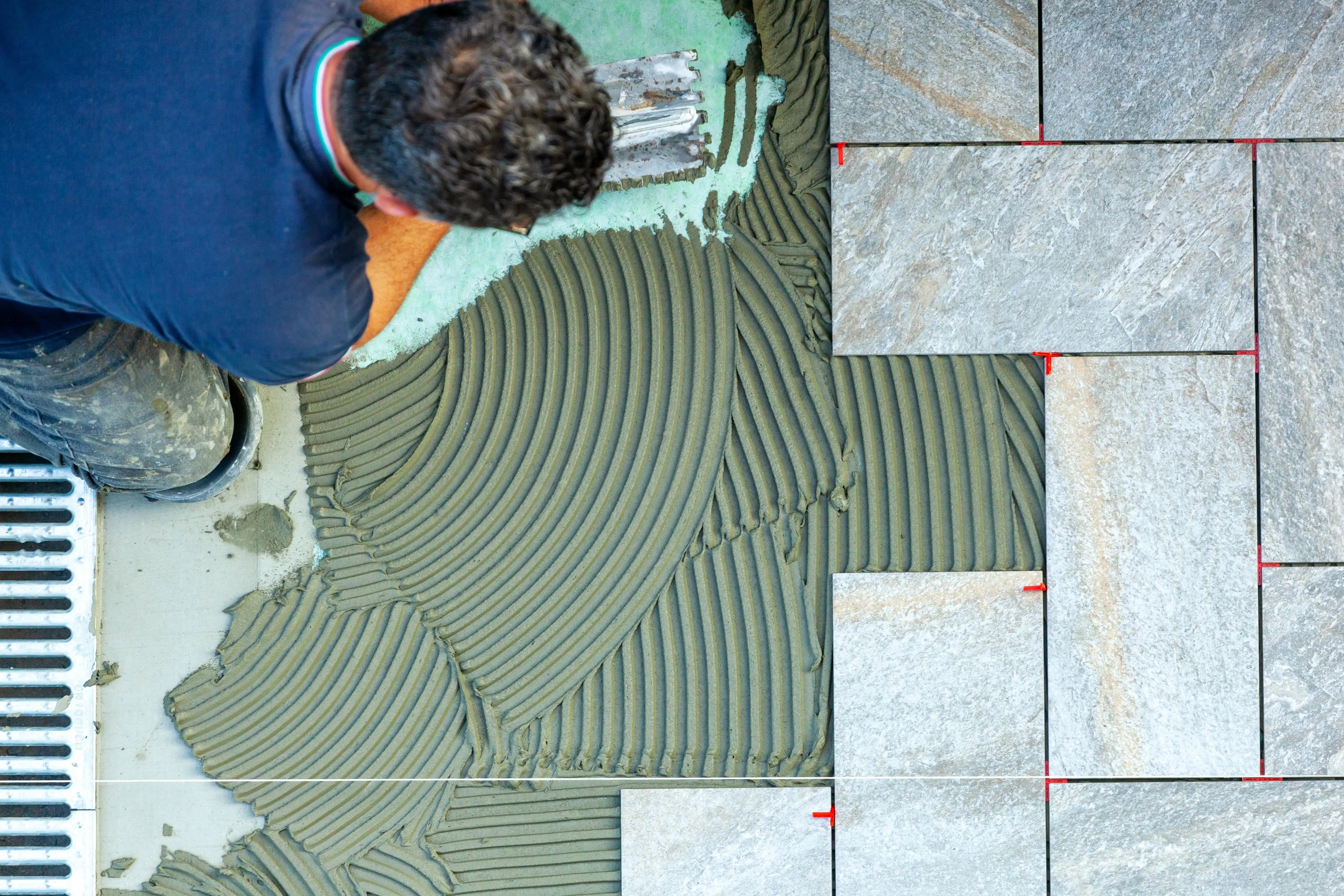 Man at work installing tiled floor with a commercial van hire for flooring installers.