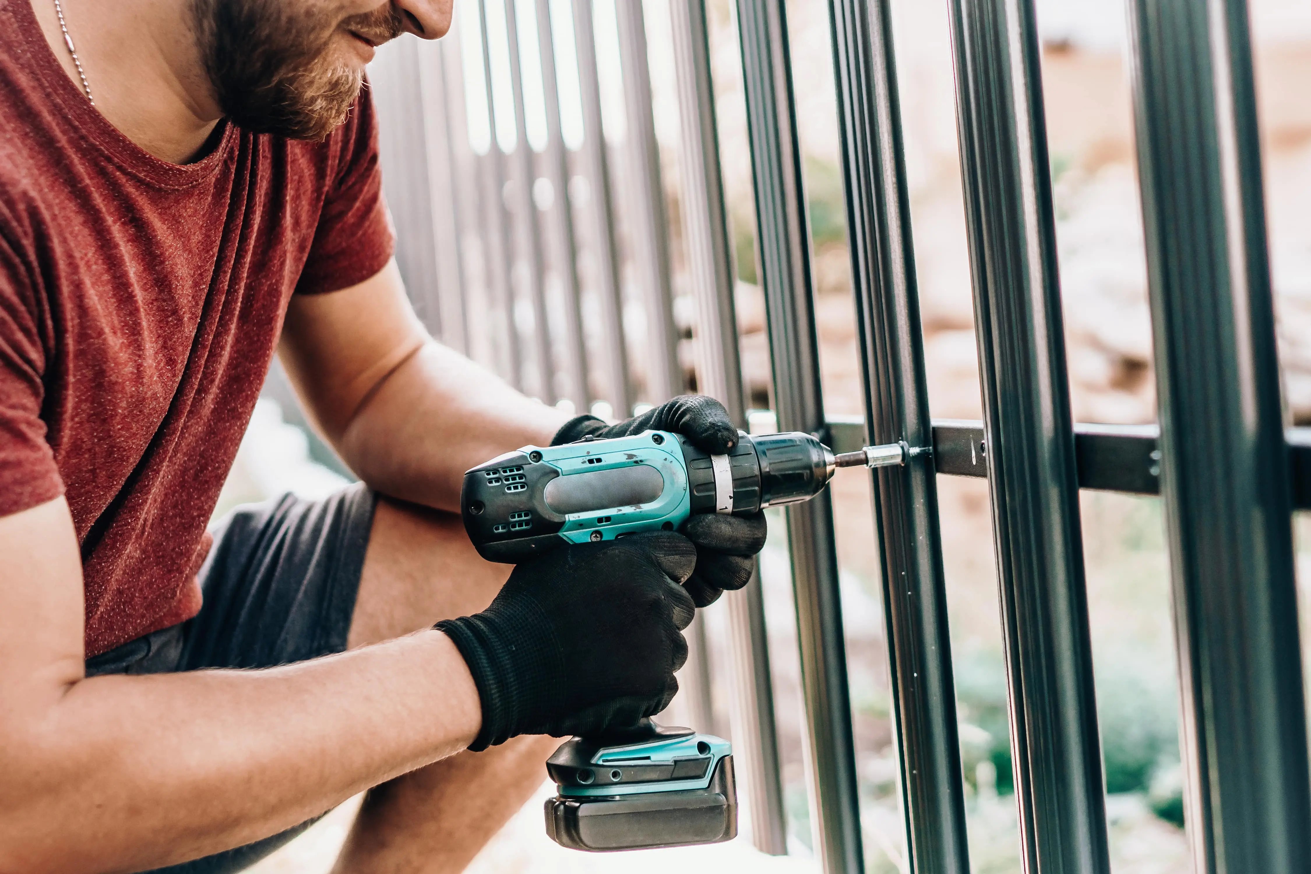 Man drilling metal fence with a commercial van hire for fencing contractors.